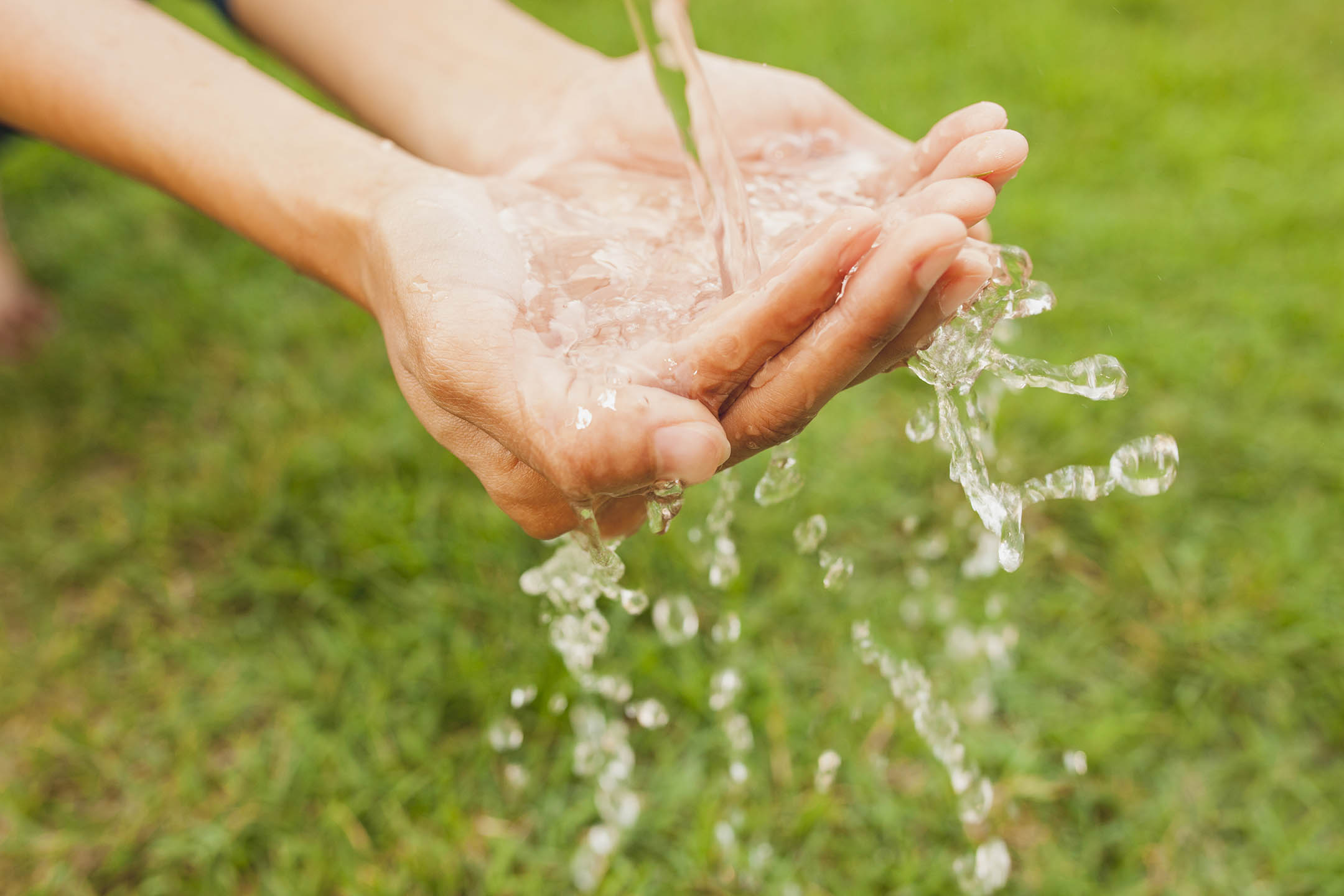 Closed cupped hands with water pouring on